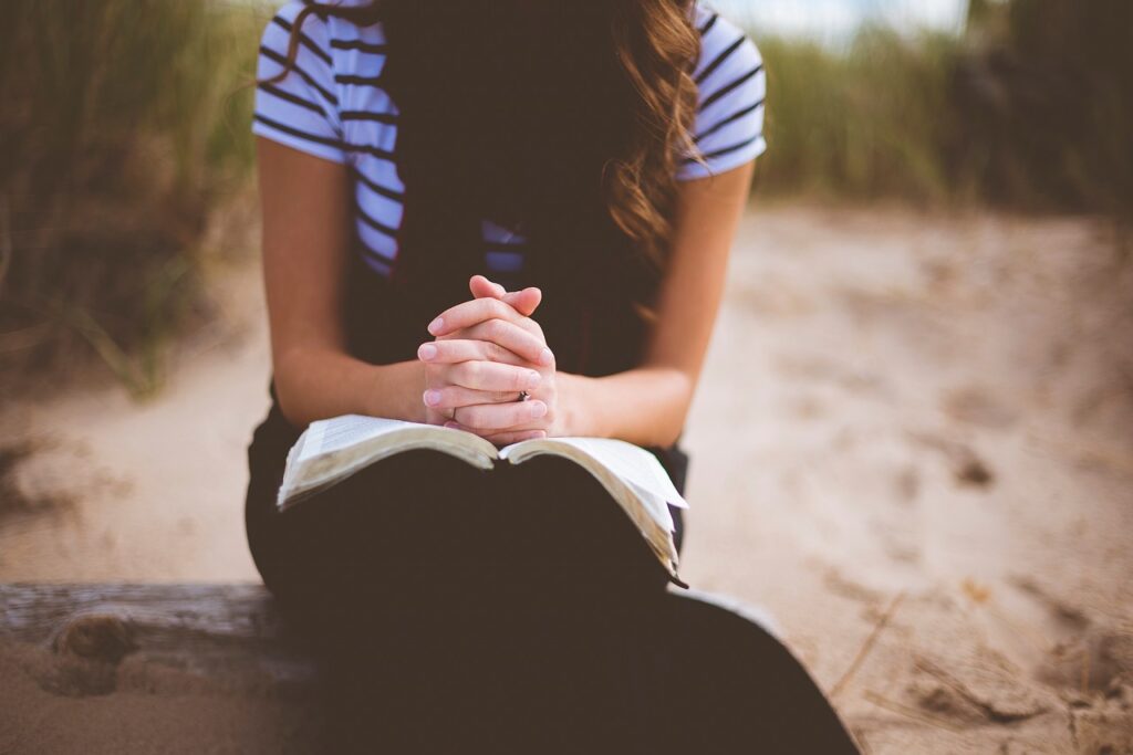 a women with long brown hair reading one of the many law of attraction books with her fingers inter locked on the book