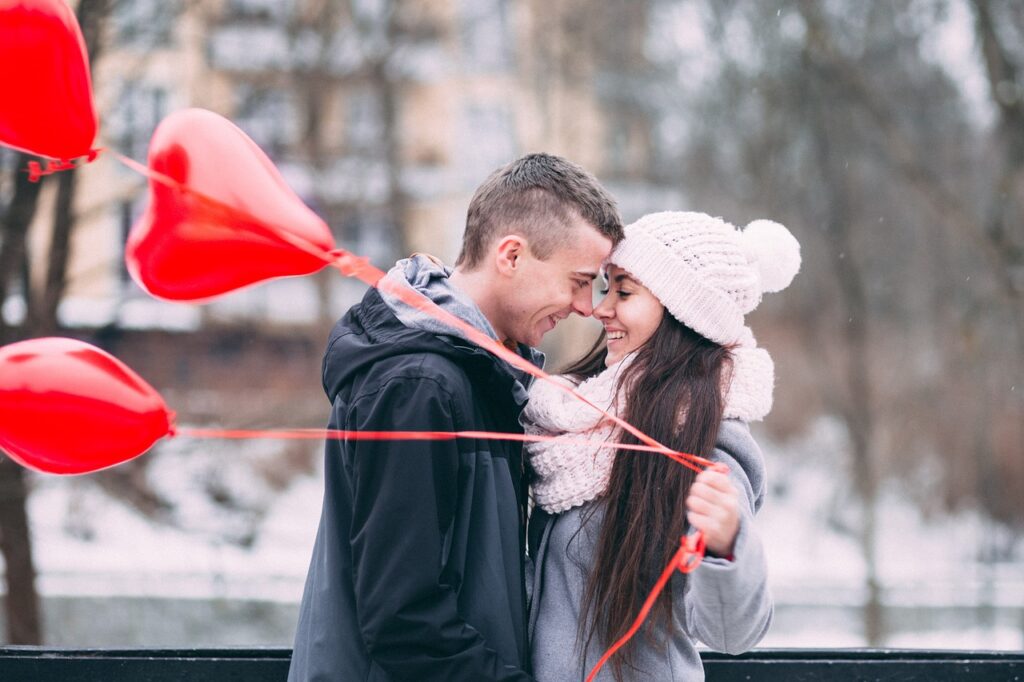a woman and a man hugging face to face holding heart shaped balloons showing the power of love