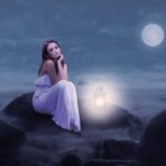a girl sitting on rocks on a moon lit night