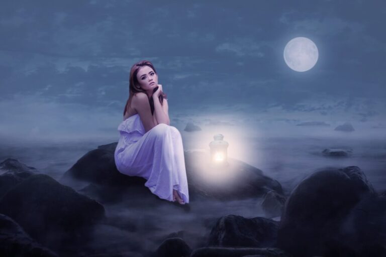 a girl sitting on rocks on a moon lit night