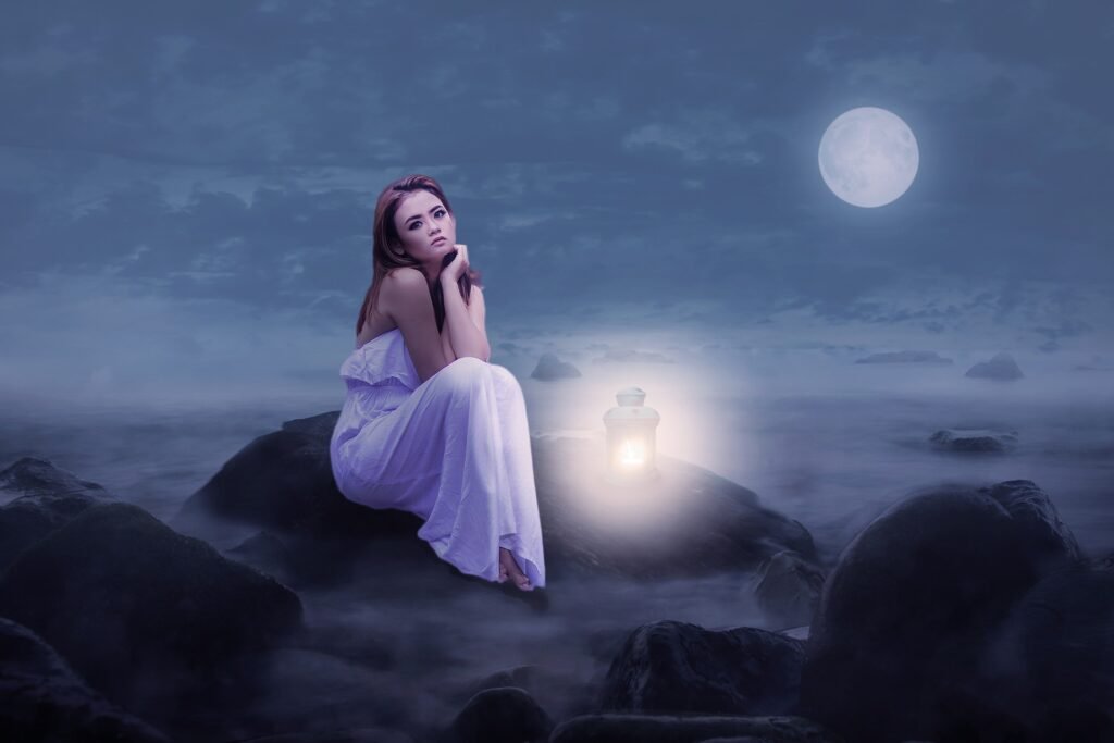 a girl sitting on rocks on a moon lit night