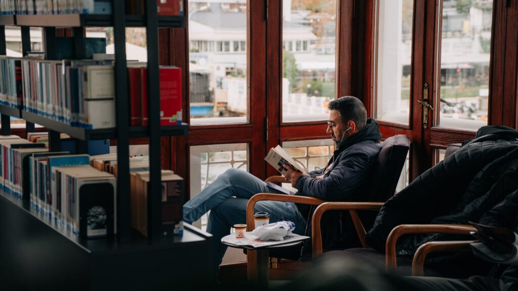 A man understands that reading books in a cozy library can boost your positive thinking