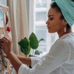 Women create a vision board with images in a stylish home setting, showcasing creativity and focus.