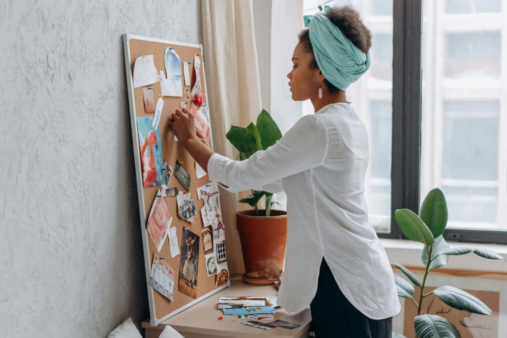 Woman in white shirt arranging a vision board to boost the power of the law of attraction