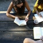 students outside at a picnic table reading books on the law of attraction