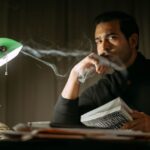 a man holding a book at his desk that has a lamp on it showing you how to boost your positive thinking by studying
