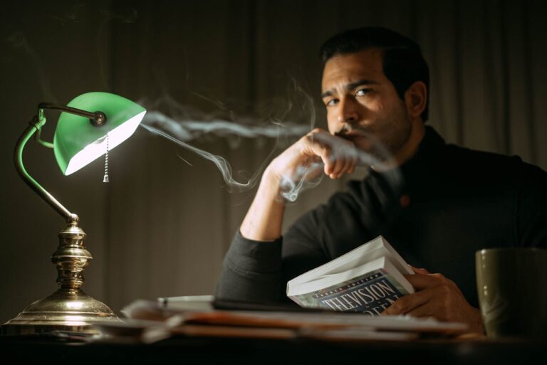 a man holding a book at his desk that has a lamp on it showing you how to boost your positive thinking by studying
