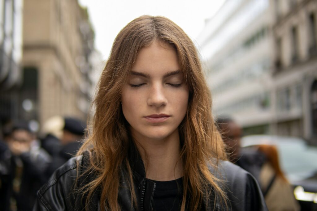 A woman in a leather jacket looking down at her cell phone